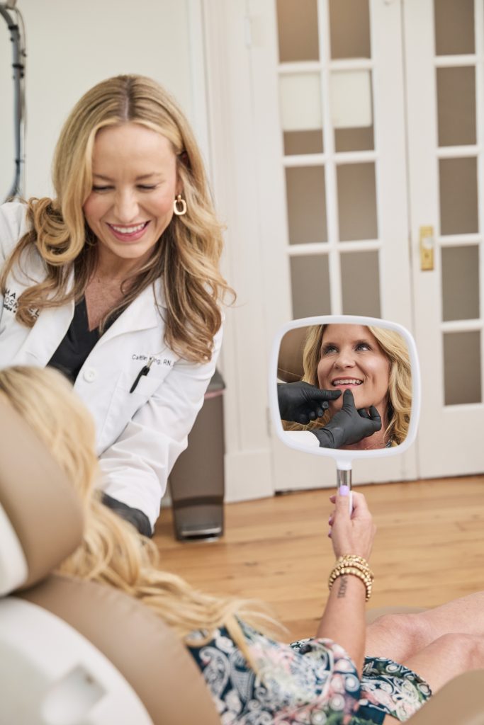 Happy MedSpa client looking in mirror with provider, showcasing results-driven skincare and client satisfaction after treatment.