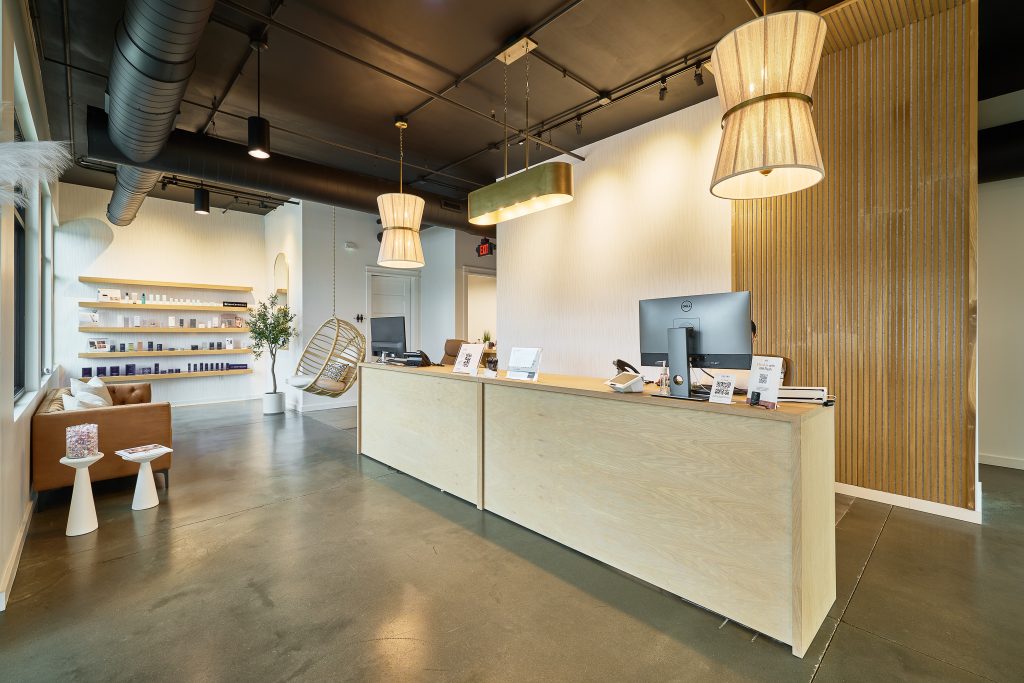 Chic MedSpa front desk area with clean lines, soft wood tones, and statement pendant lights, reflecting modern MedSpa decor trends.