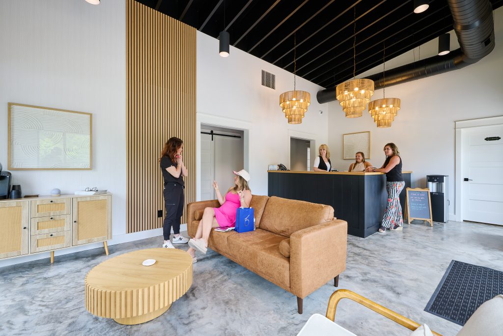 Modern MedSpa decor featuring minimalist seating, floating retail shelves, and neutral tones for a serene reception experience.