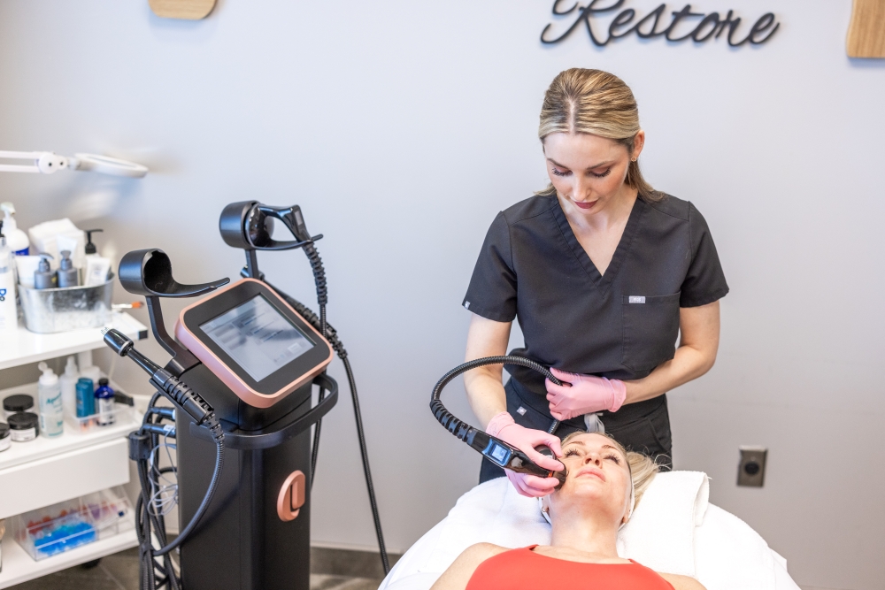 Female MedSpa provider performing a facial treatment using an advanced radiofrequency device on a female client in a professional treatment room.