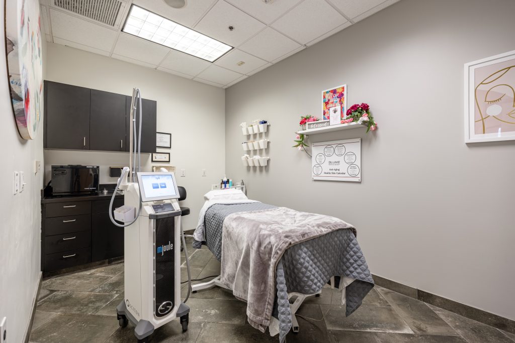 Private MedSpa treatment room featuring a treatment bed, mJoule laser system, and neatly organized skincare products, designed for advanced cosmetic procedures